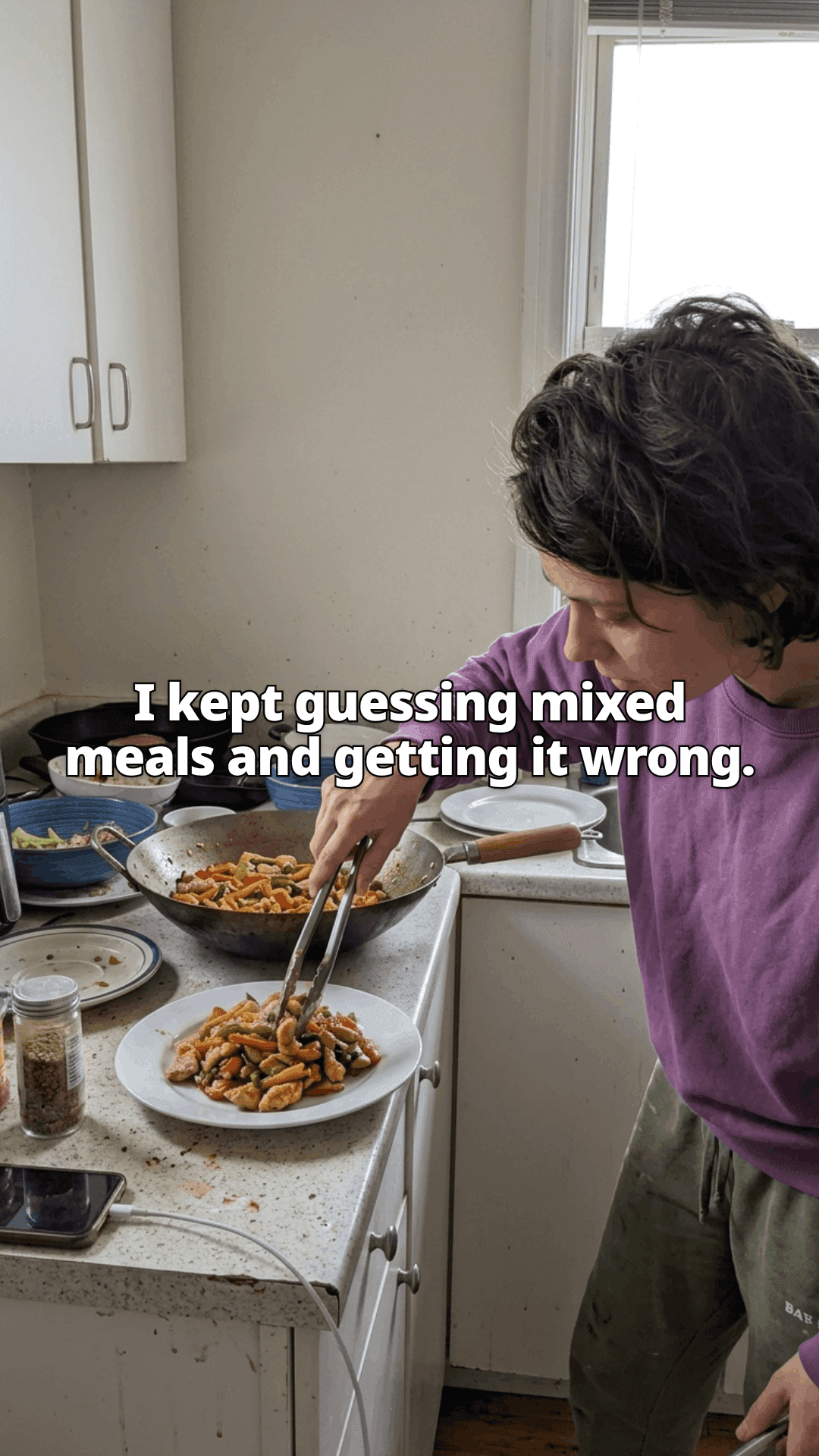 A woman leaning over a stove, lifting stir fry out of a wok onto a plate with tongs, used pans and dishes around her, with a line of the post across the photo.